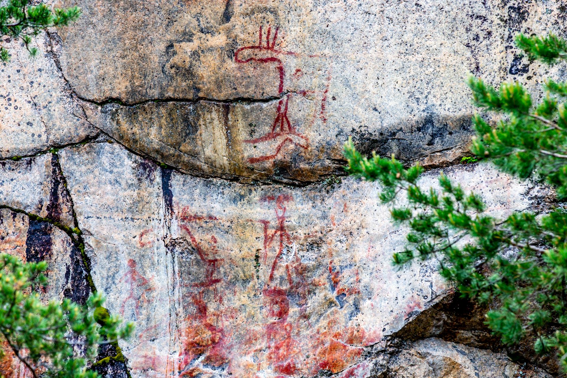 Hirveä ja ihmishahmoja esittäviä kalliomaalauksia.