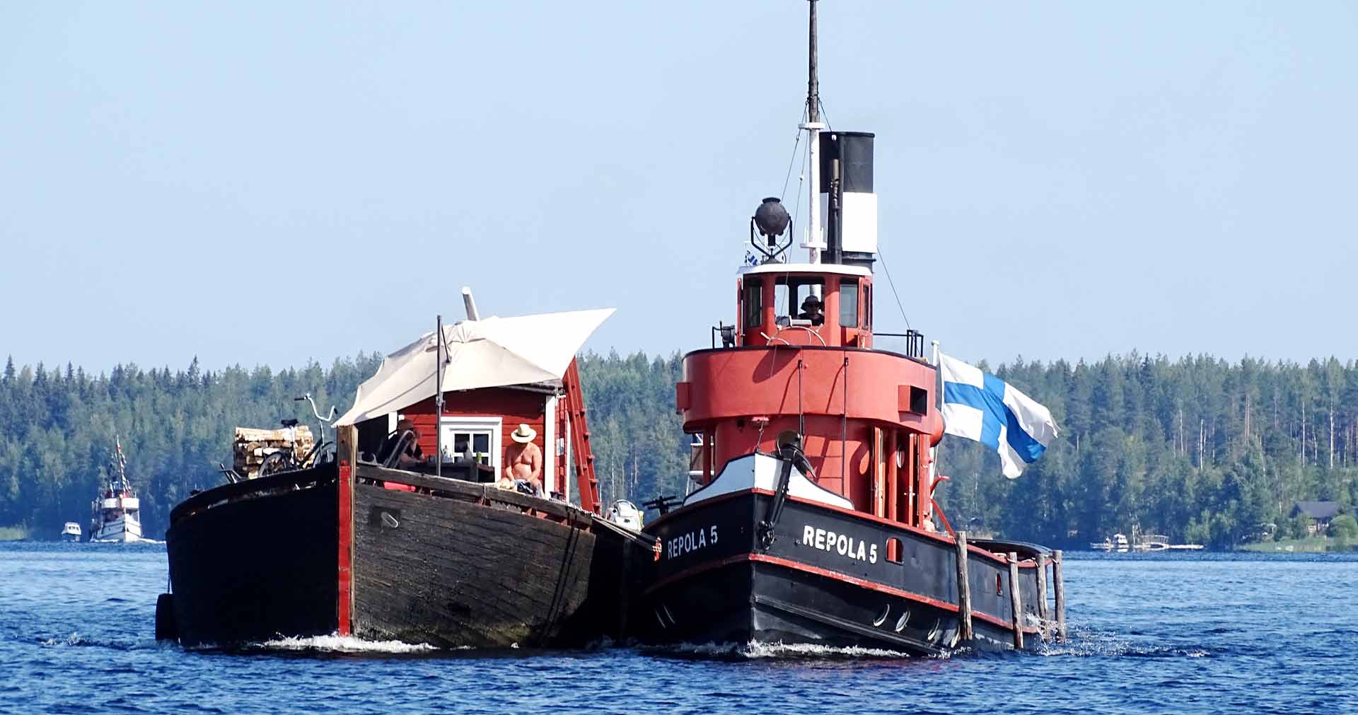 Vanha höyrylaiva ja lotja seilaavat järvellä vierekkäin.