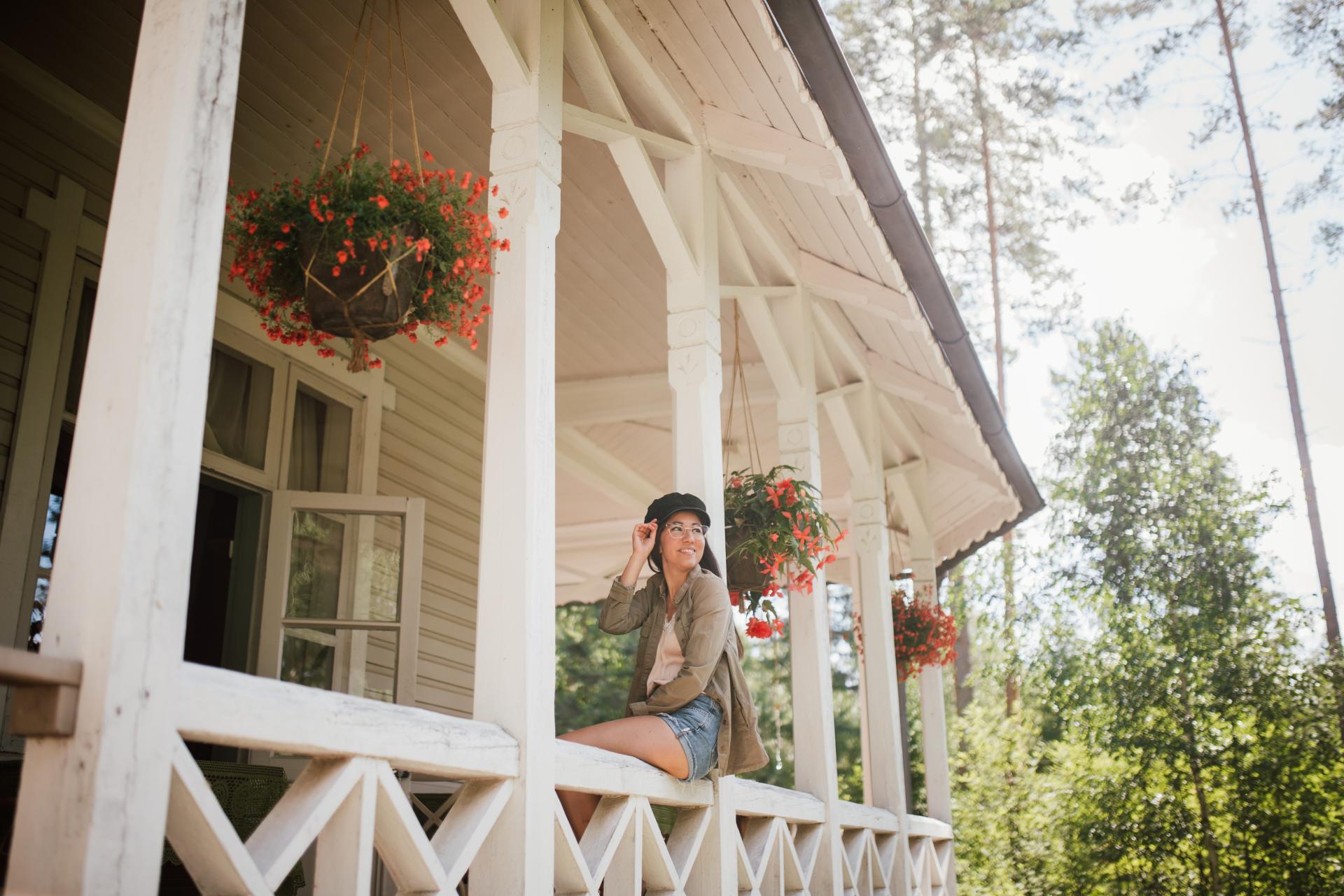 Eine Frau sitzt auf einer Veranda einer Villa.