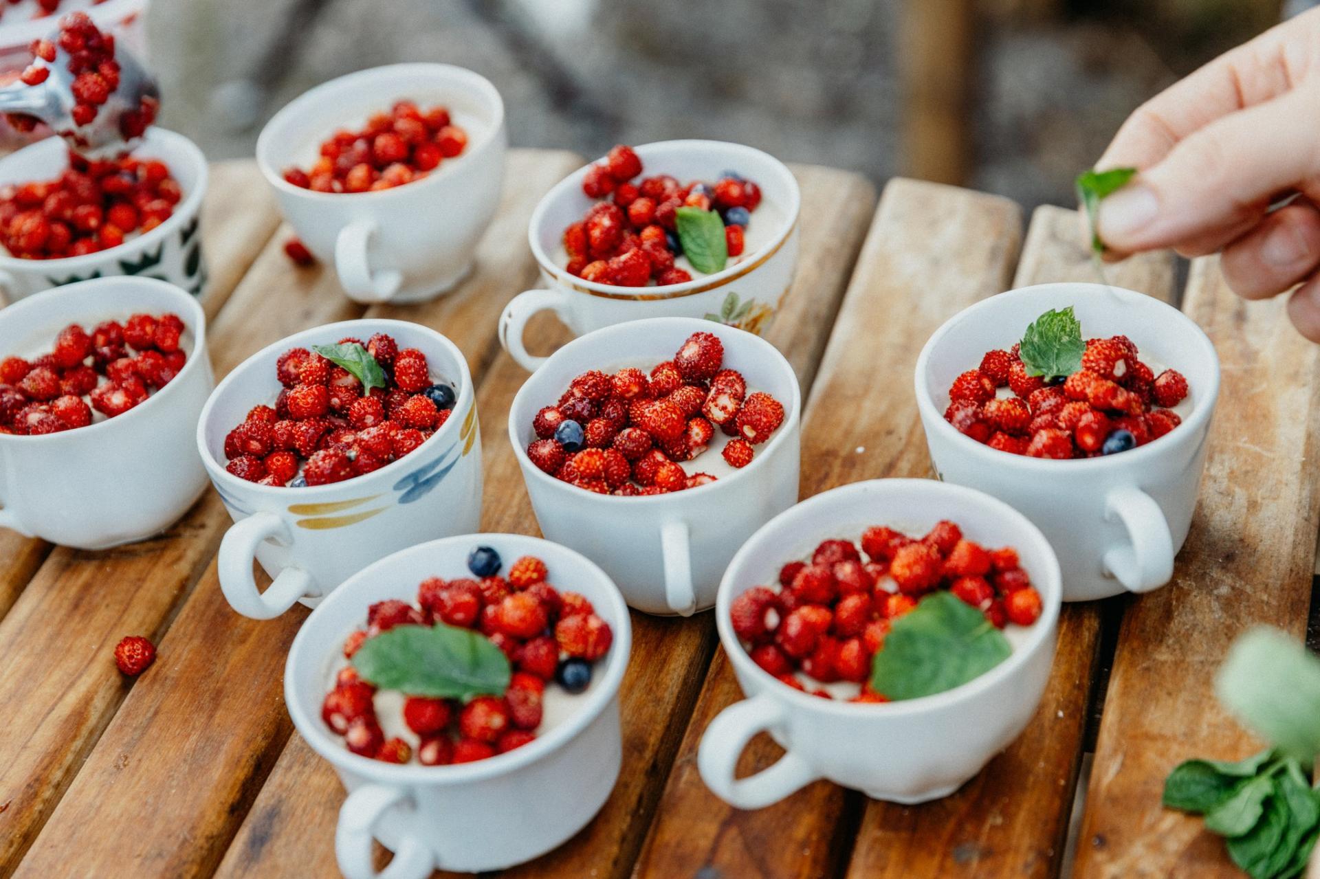 A dessert with wild strawberries on top served in coffee cups. 