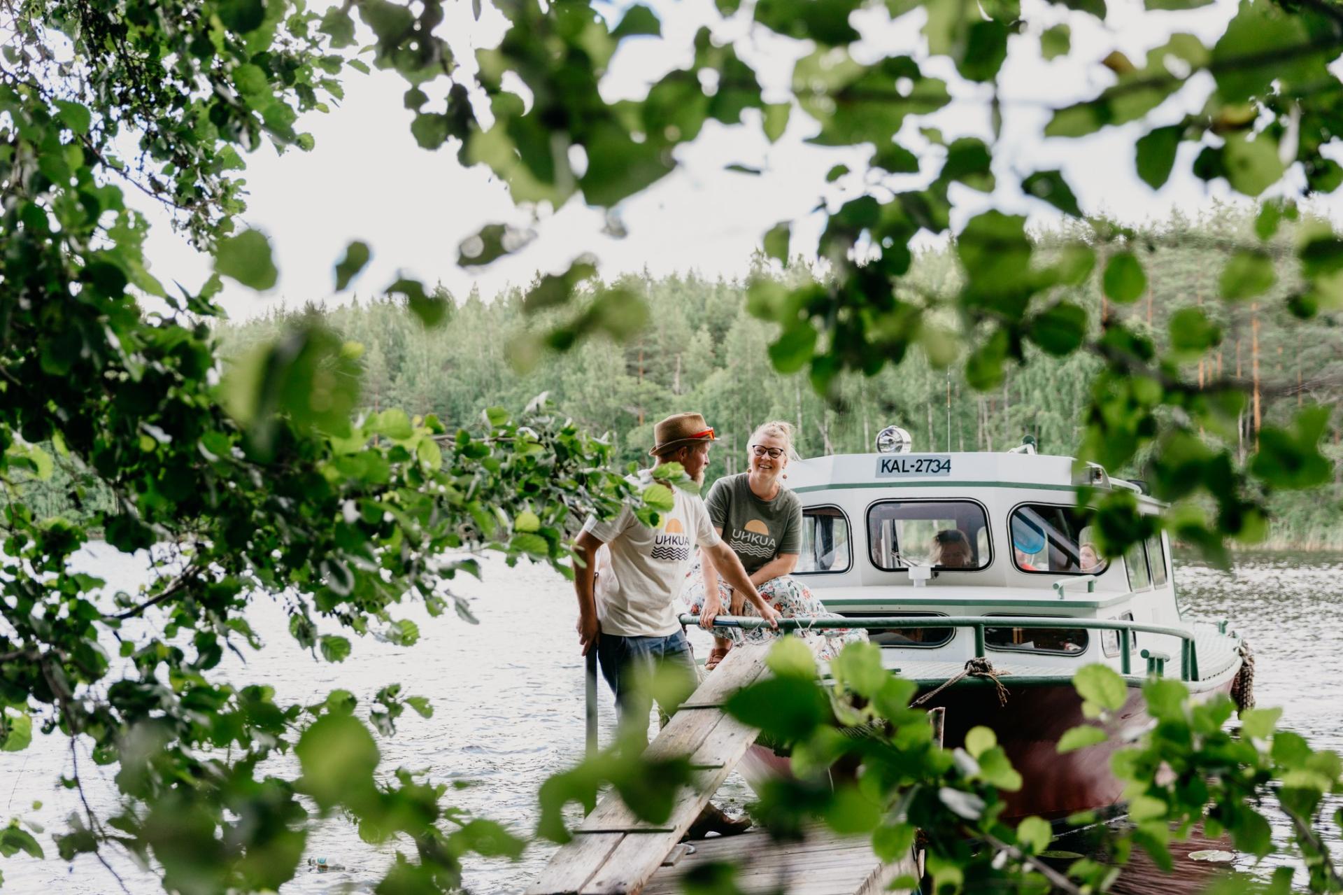 A man and a woman on a peer to which a motor boat is docked. 