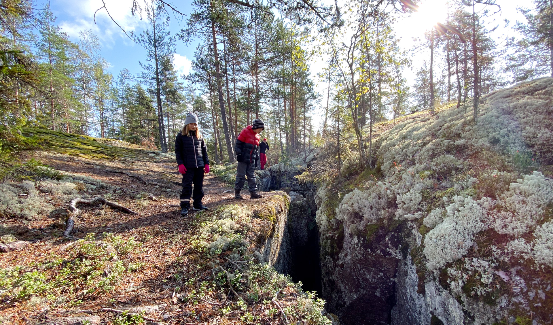 Tyttö ja poika katselevat kalliossa olevaa syvää halkeamaa.