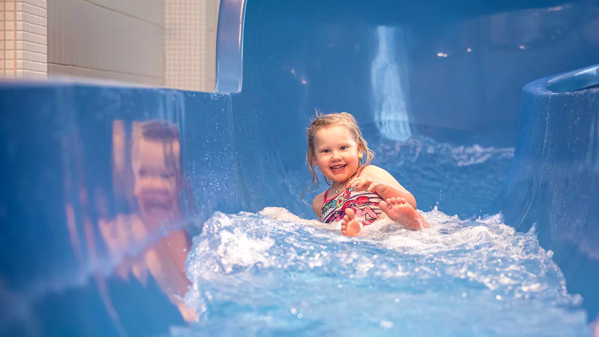 Pieni tyttö laskee vesiliukumäestä.